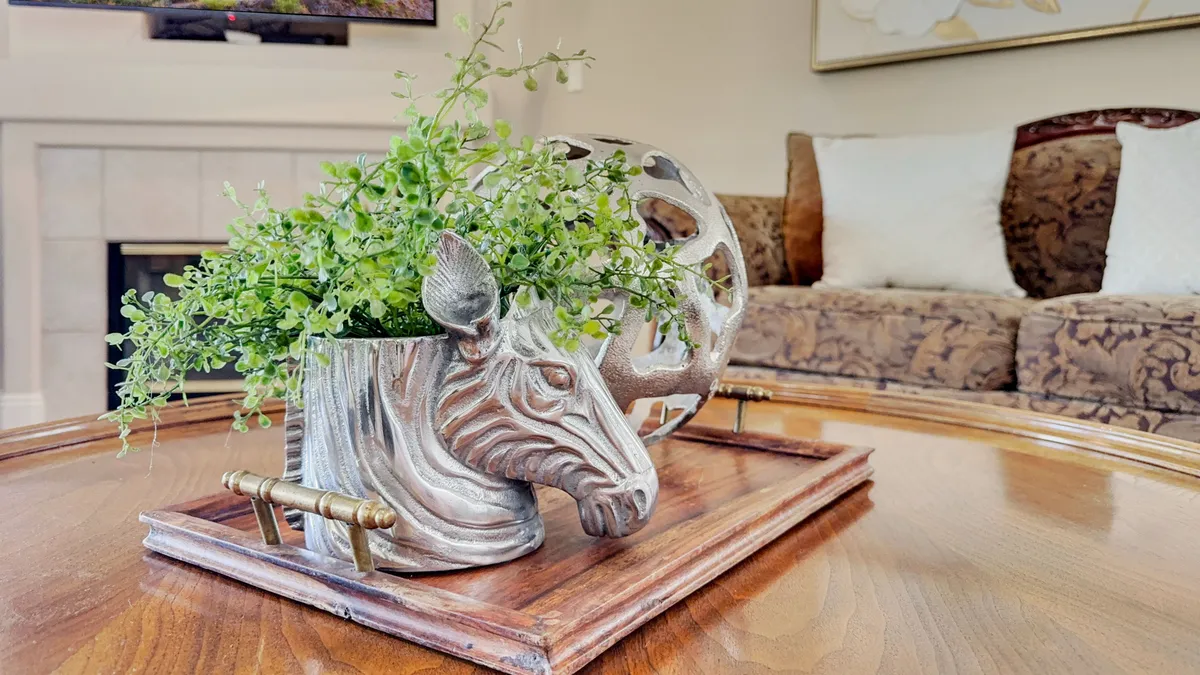 A cozy indoor seating area with a playful zebra planter, lush greenery, and a wooden tray, creating an inviting space for socializing or relaxing. The arrangement emphasizes personality and comfort, with natural light suggesting a connection to the outdoors.