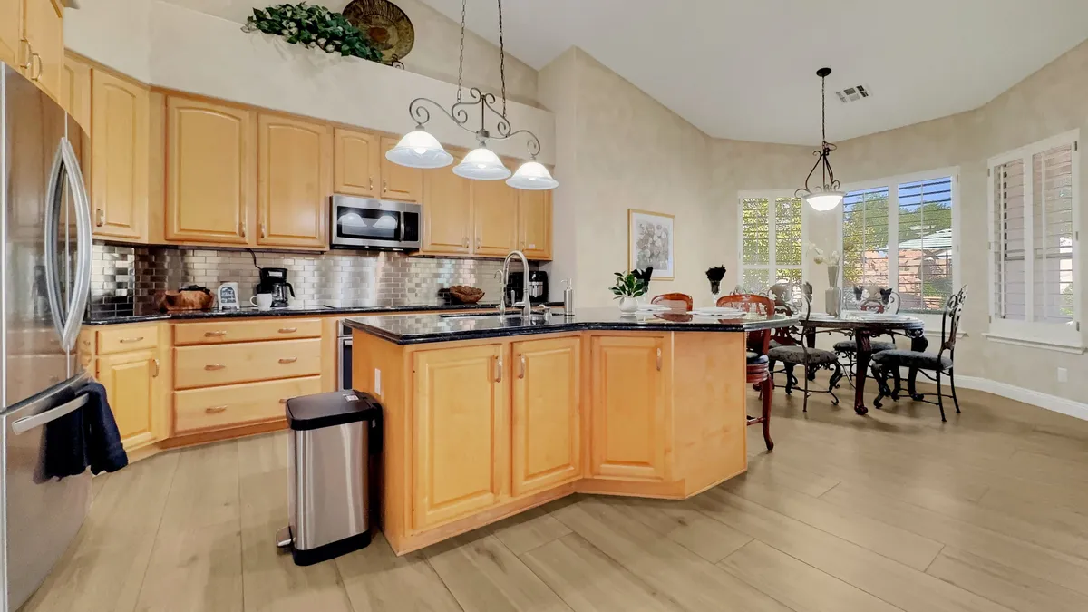 A spacious kitchen with a large central island, dining table, modern appliances, and abundant natural light pouring in from the windows. The layout emphasizes the open flow between cooking, dining, and gathering areas, illustrating a perfect space for group meal preparation and shared experiences.
