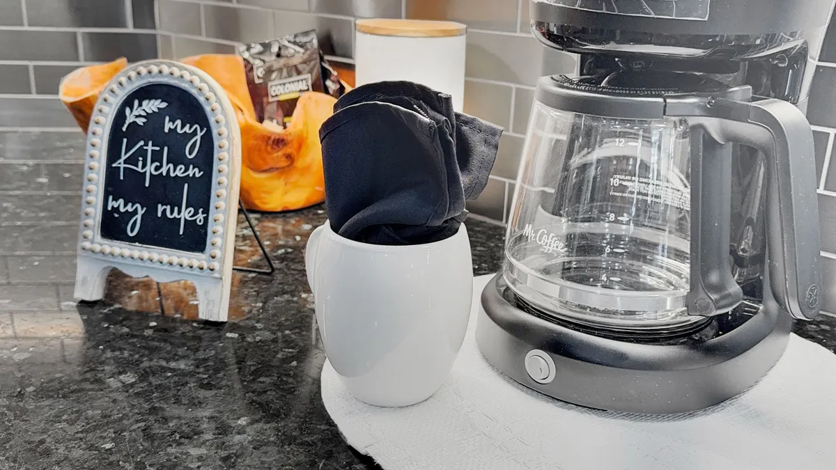 A warm, welcoming kitchen scene featuring a coffee maker, a chalkboard sign, and a white vase with napkins. The space feels lived-in, ideal for gathering with family and friends over morning coffee or meals prepared after exploring local events.