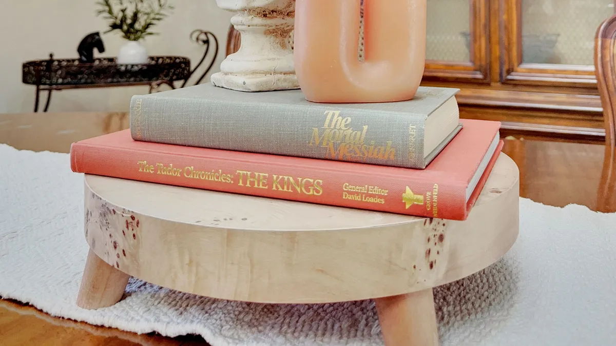 A wooden table adorned with a stack of books and a decorative object, creating a cozy nook ideal for reading or working. The ambiance is peaceful, suggesting a dedicated spot for productive focus or relaxation.